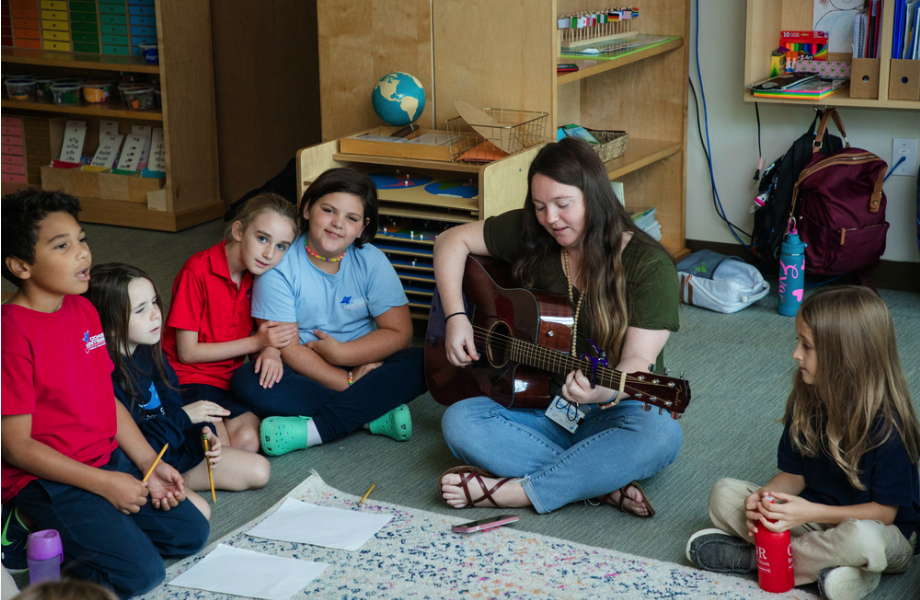 Students sing to teacher playing guitar